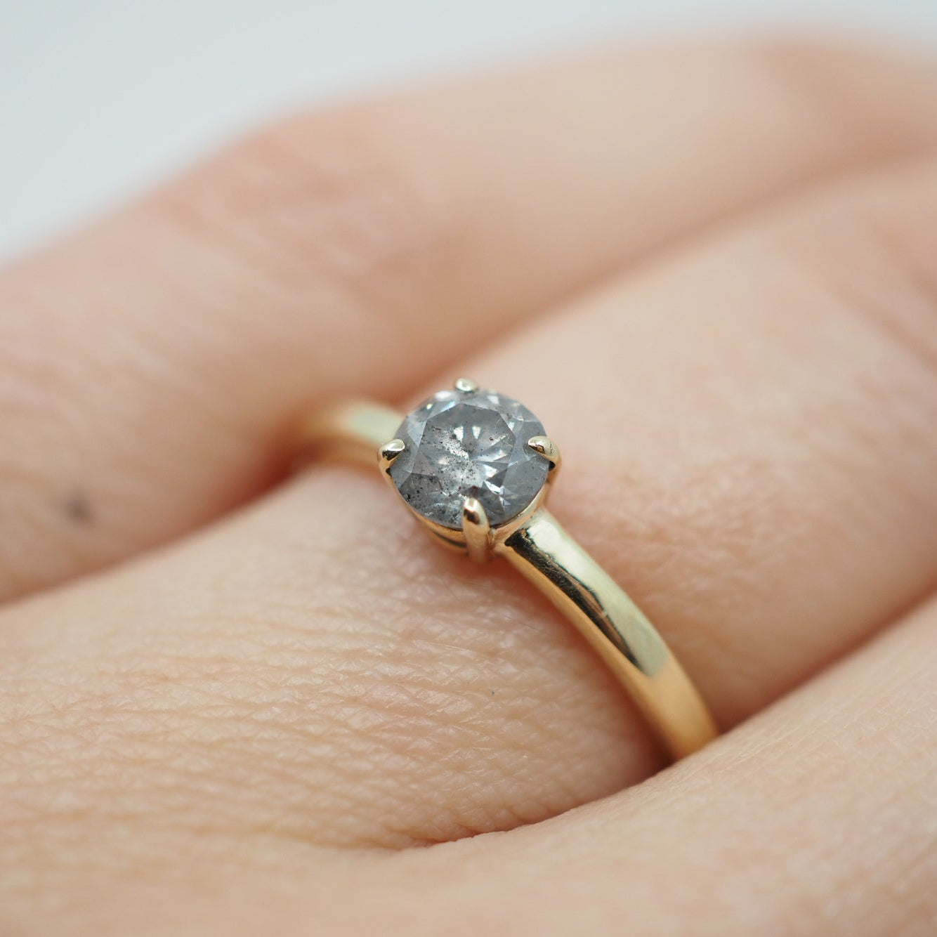 Gold ring with a diamond on a hand against a light background