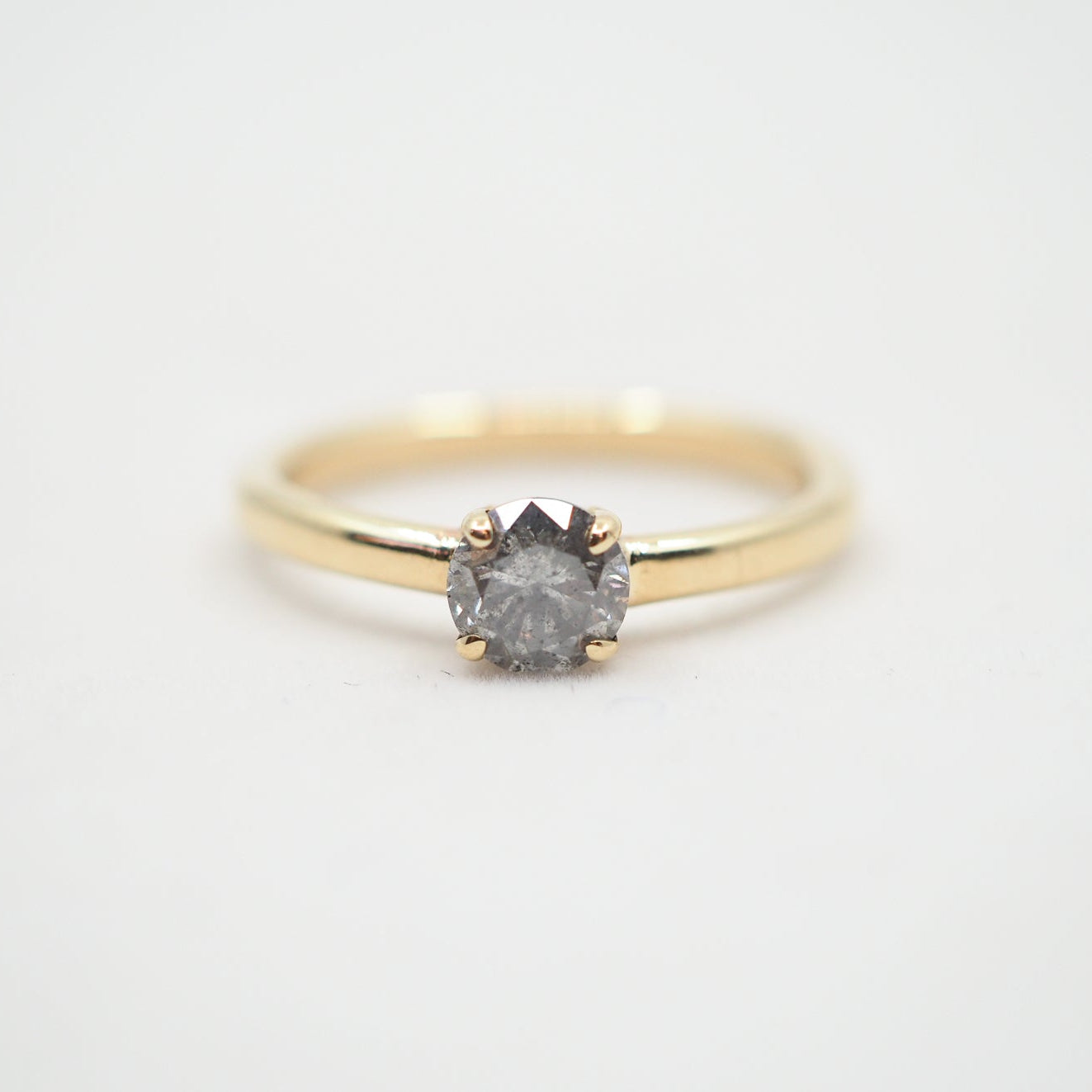 Gold ring with a diamond on a light gray background