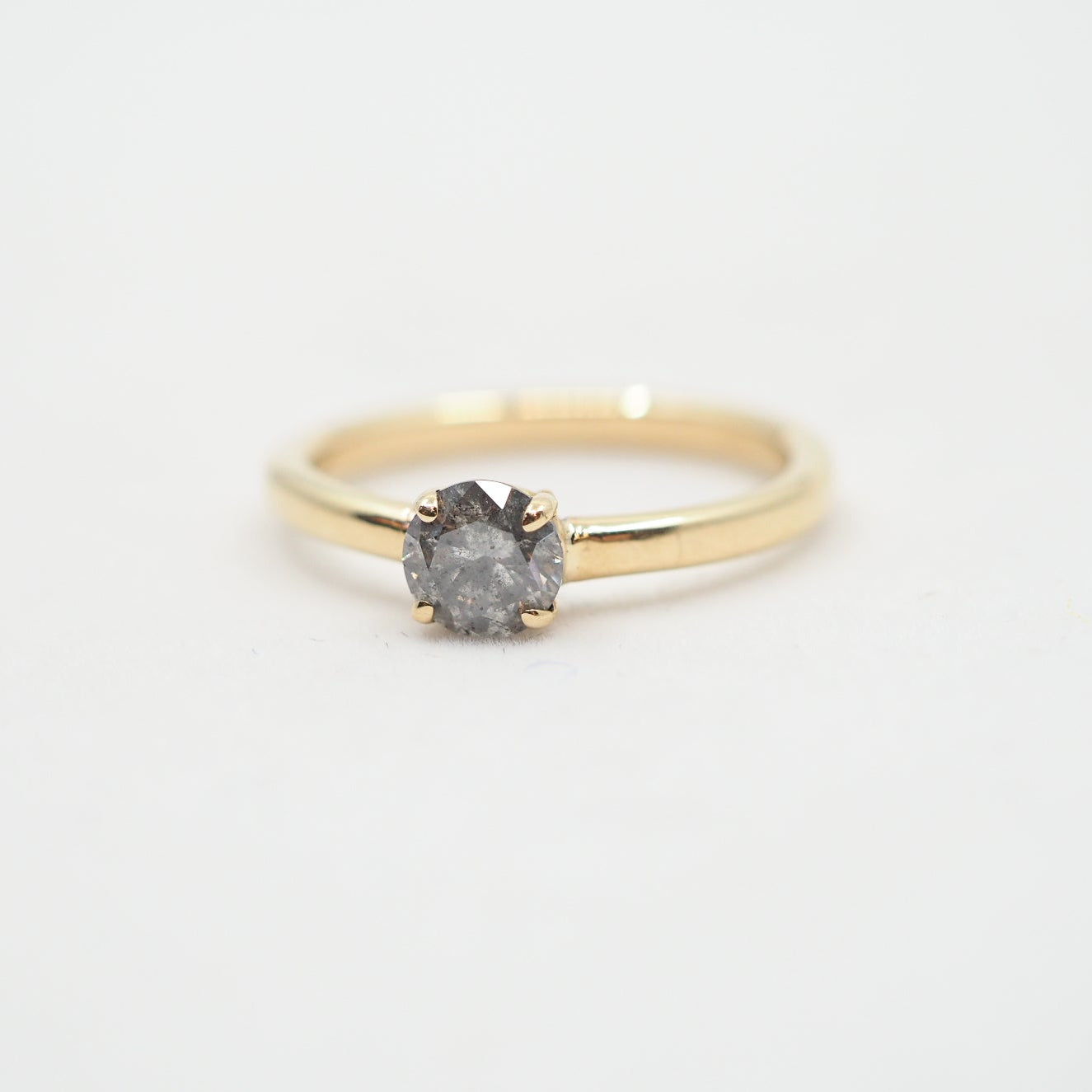 Gold ring with a diamond on a light gray background