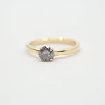 Gold ring with a diamond on a light gray background