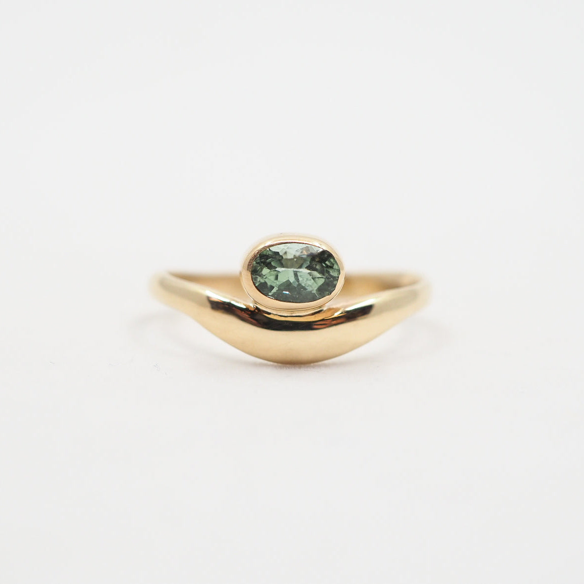 Gold ring with a green gemstone on a white background