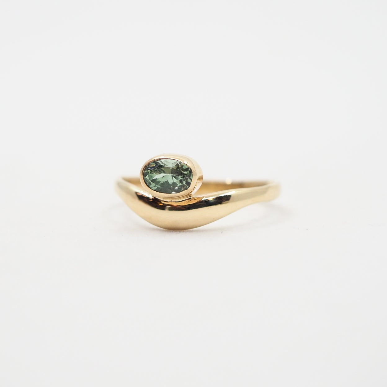Gold ring with a green gemstone on a white background