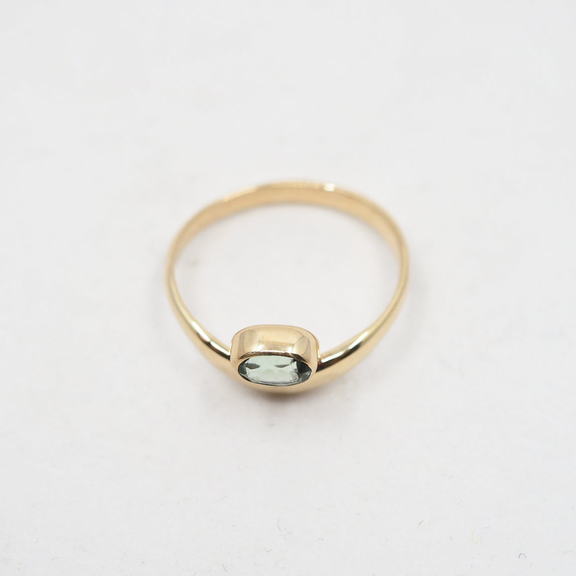 Gold ring with a green gemstone on a white background