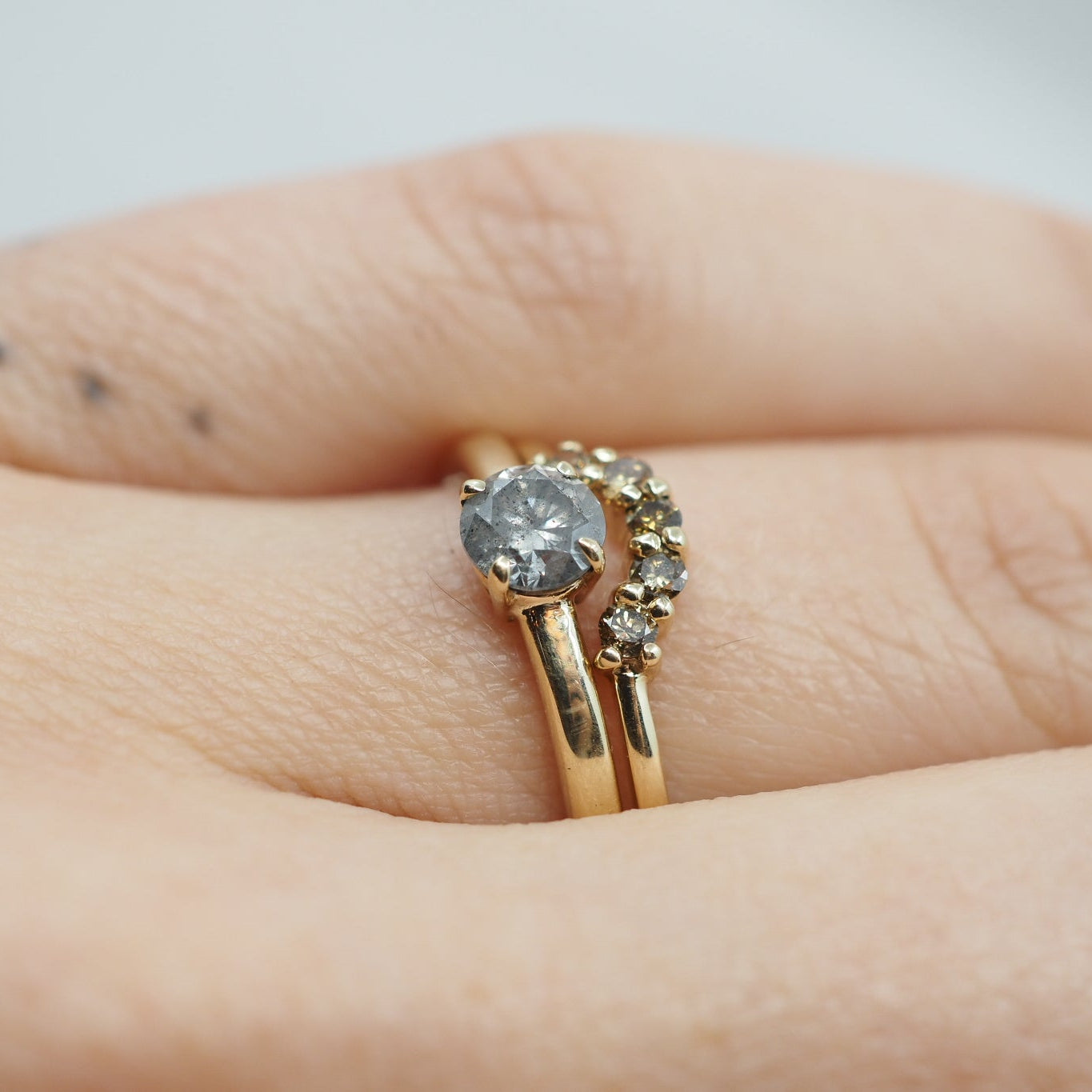 Gold ring with a diamond on a finger against a neutral background