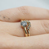Gold ring with a diamond on a finger against a neutral background