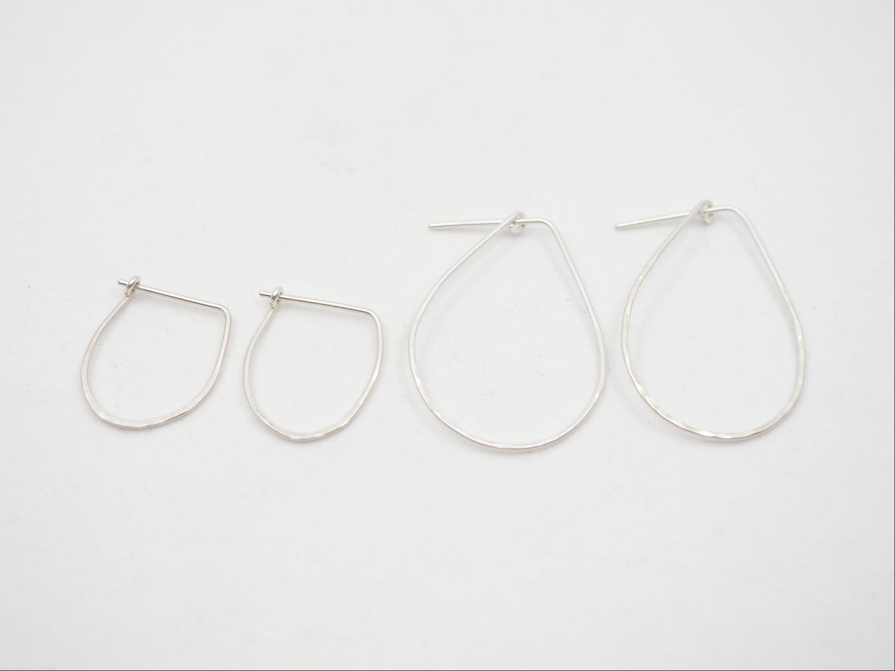 Set of four silver hoop earrings on a white background