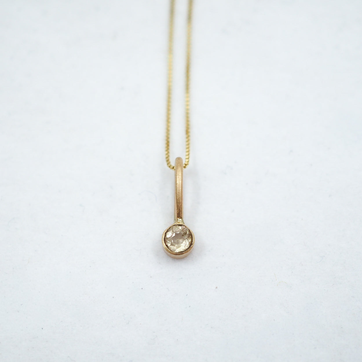 Gold necklace with a small pendant on a white background