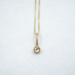 Gold necklace with a small pendant on a white background