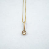 Gold necklace with a small pendant on a white background