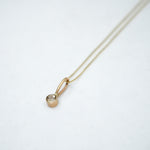 Gold necklace with a small pendant on a white background