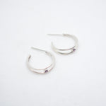 Pair of silver hoop earrings on a light gray background