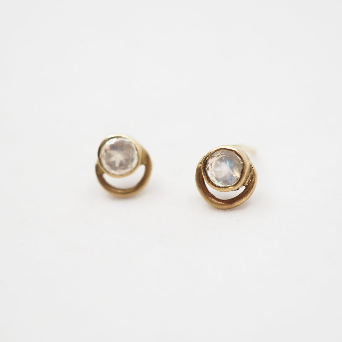 Pair of gold earrings with moonstone stones on a white background