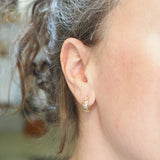 Close-up of a person wearing gold hoop earrings with a blurred background