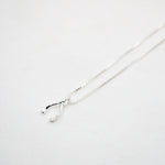 Silver necklace with a wishbone pendant on a light gray background