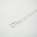 Silver necklace in the shape of a wishbone on a light gray background