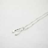 Silver necklace in the shape of a wishbone on a light gray background