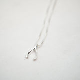 Silver wishbone pendant necklace on a white background