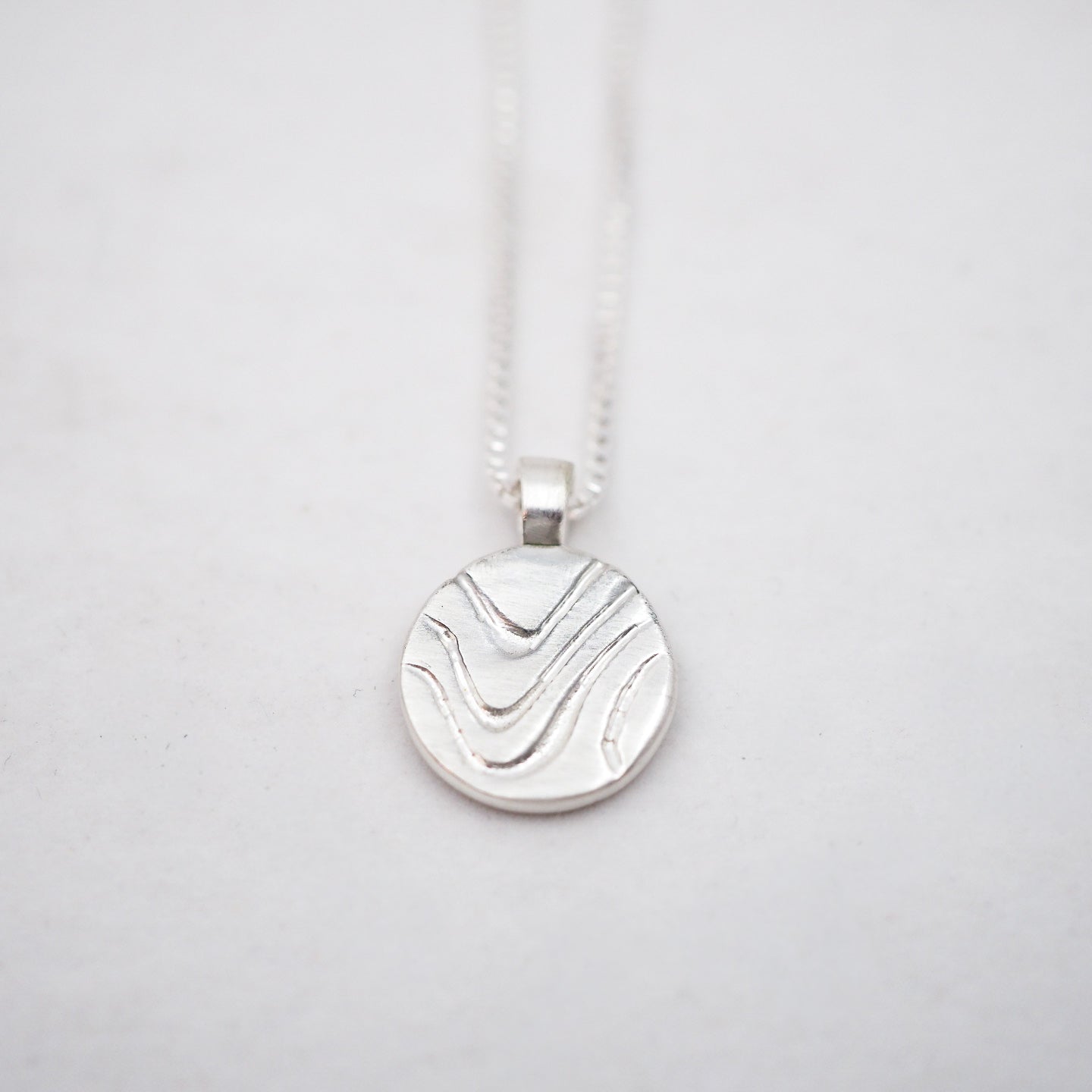 Silver pendant necklace on a light gray background