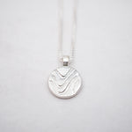 Silver pendant necklace on a light gray background