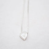 Silver heart-shaped pendant on a white chain against a light gray background