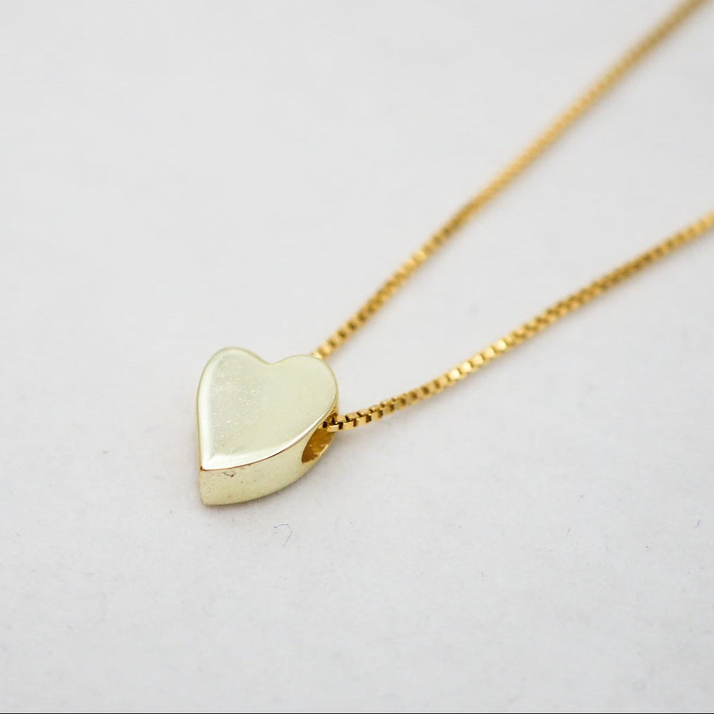 Gold heart-shaped pendant necklace on a light gray background