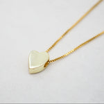 Gold heart-shaped pendant necklace on a light gray background