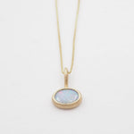 Gold necklace with an opal pendant on a white background