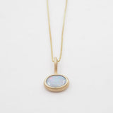 Gold necklace with an opal pendant on a white background