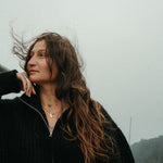 Woman with long hair against a foggy background wearing a pendant jumble on the charm connector. 