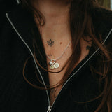 Person with long hair and necklaces against a blurred background