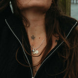 Person with long hair and necklaces against a blurred background