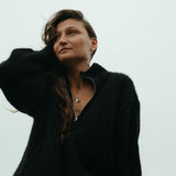 Woman wearing a black jacket and pink pants against a light gray background