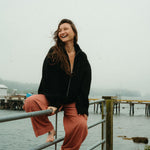 Woman sitting on a railing by a body of water with a foggy background