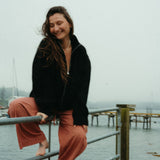 Woman sitting on a railing by a body of water on a foggy day