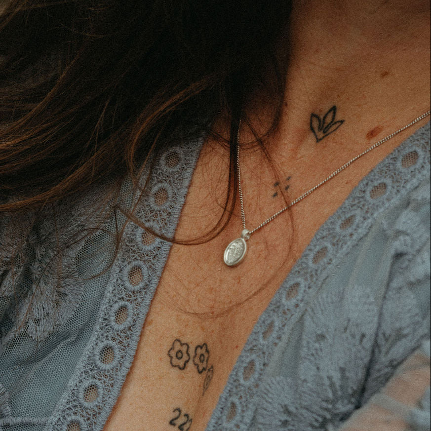 Close-up of a person wearing a lace garment with visible tattoos on their neck and chest.
