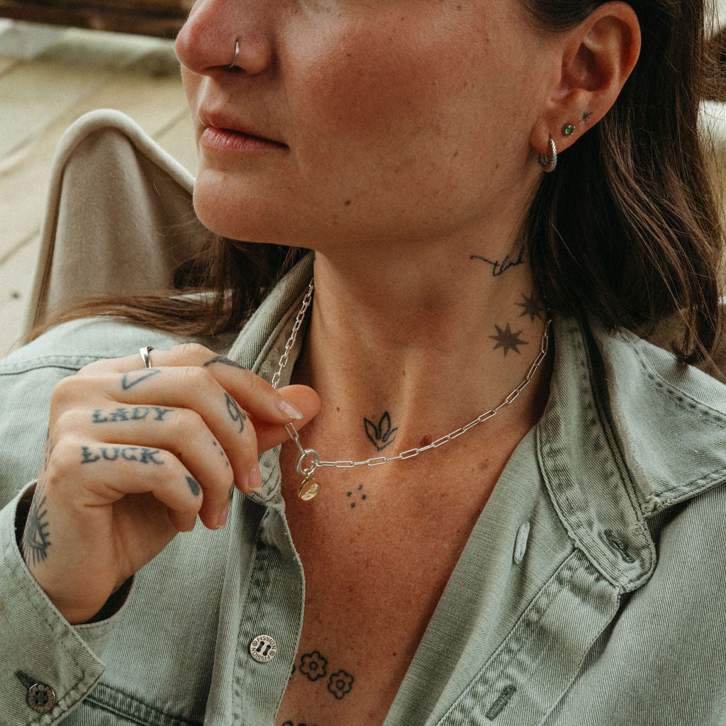 Woman wearing a light green denim jacket with visible tattoos on her neck and arms.