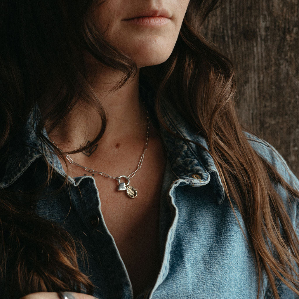Woman with tattoos on her hands wearing a denim shirt against a wooden background