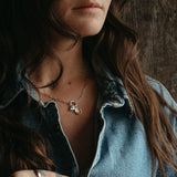 Woman with tattoos on her hands wearing a denim shirt against a wooden background