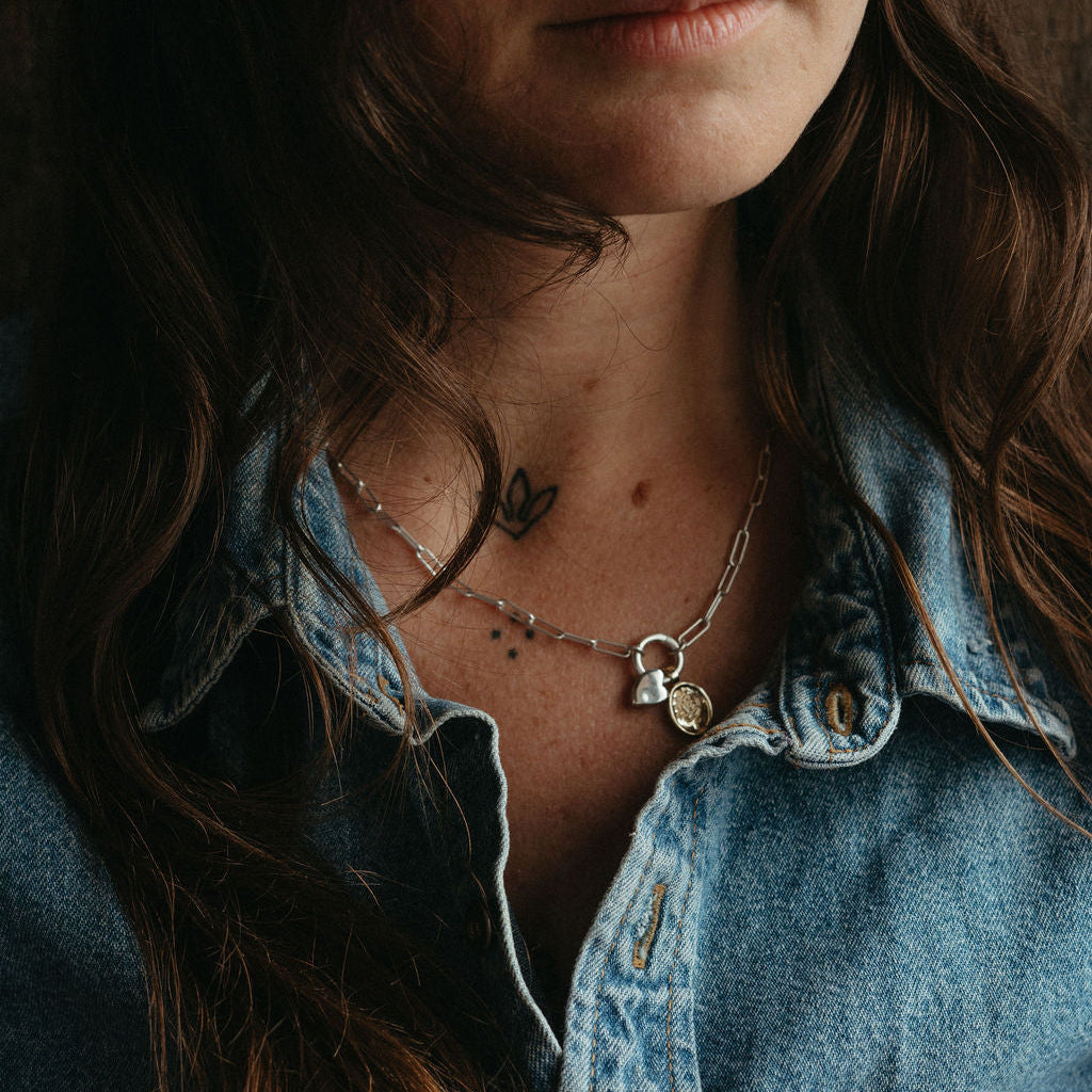 Close-up of a person wearing a denim jacket with visible jewelry.