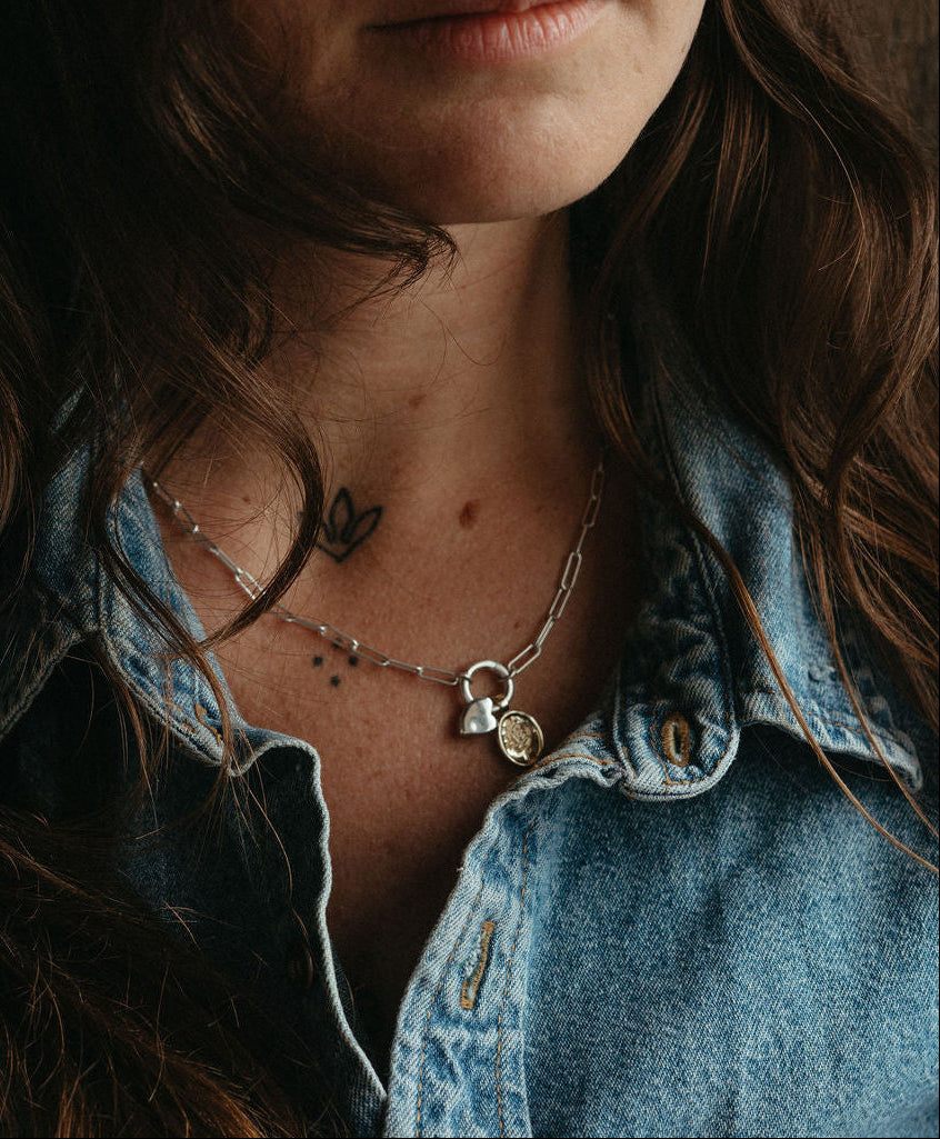 Close-up of a person wearing a denim jacket with visible jewelry.