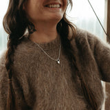 Person wearing a brown sweater sitting indoors with a blurred background