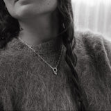 Black and white photo of a person wearing a textured sweater and a heart pendant necklace.