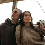 Two people standing close together under a wooden structure.