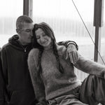 Black and white photo of a couple sitting close together indoors.