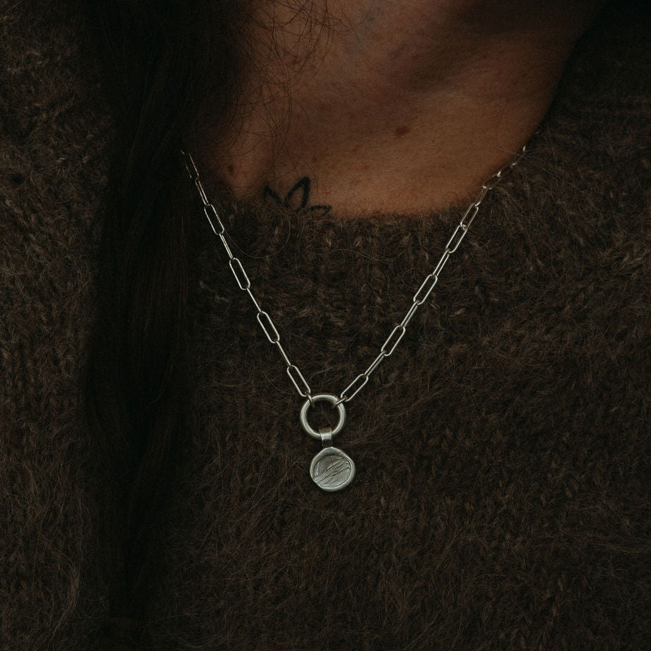 Silver necklace with a pendant on a dark background