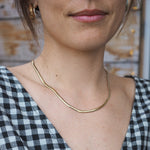 Person wearing a gold necklace with a checkered fabric background