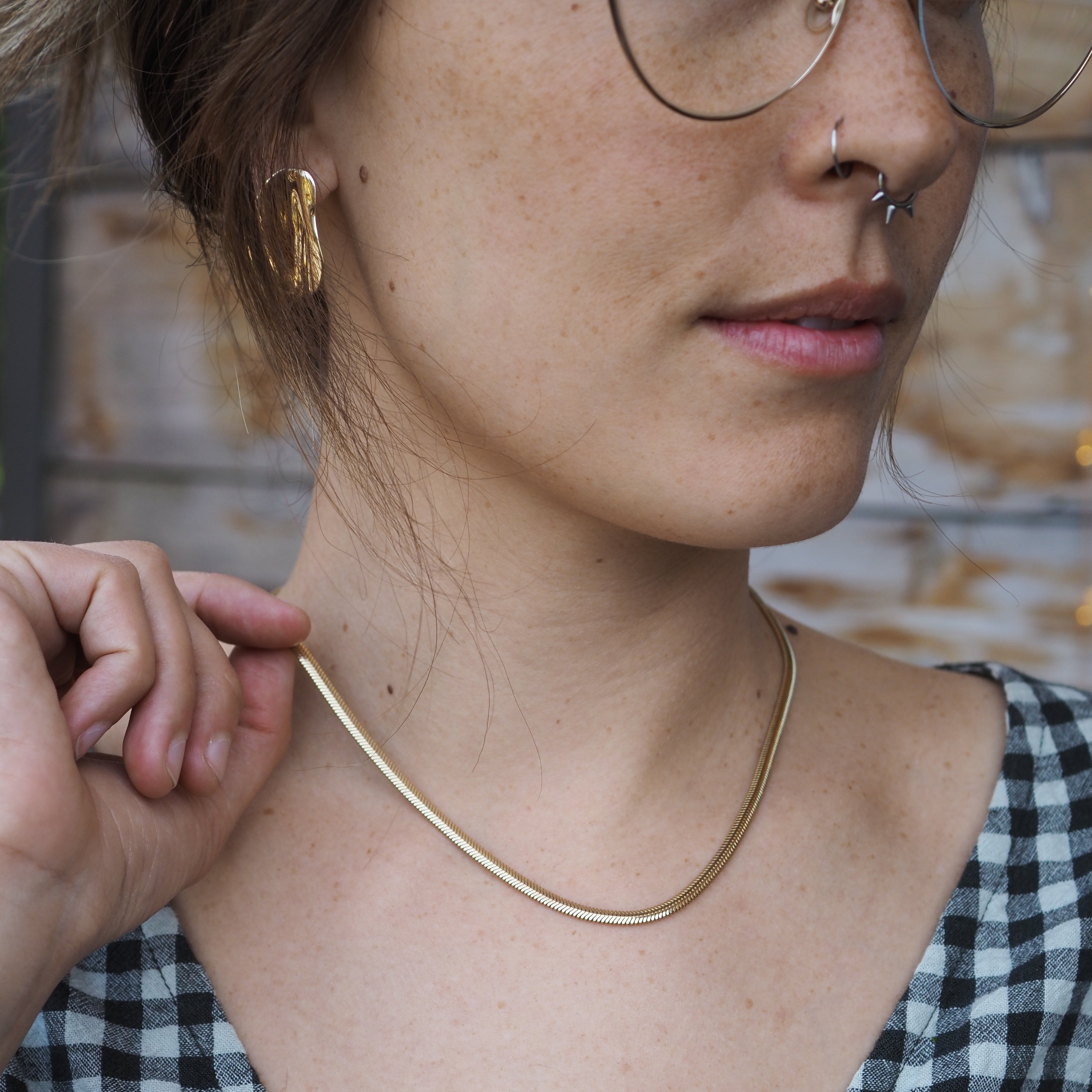 Person wearing a gold necklace with a checkered fabric background
