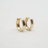 A pair of polished gold huggie hoop earrings on a clean, light gray background.