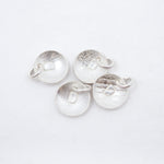 Four round silver disc charms with letter D textured finishes and small attached loops, arranged on a plain white background.