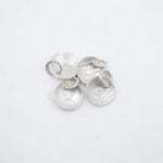 Four textured silver disc charms with attached jump rings, displayed on a clean white background.